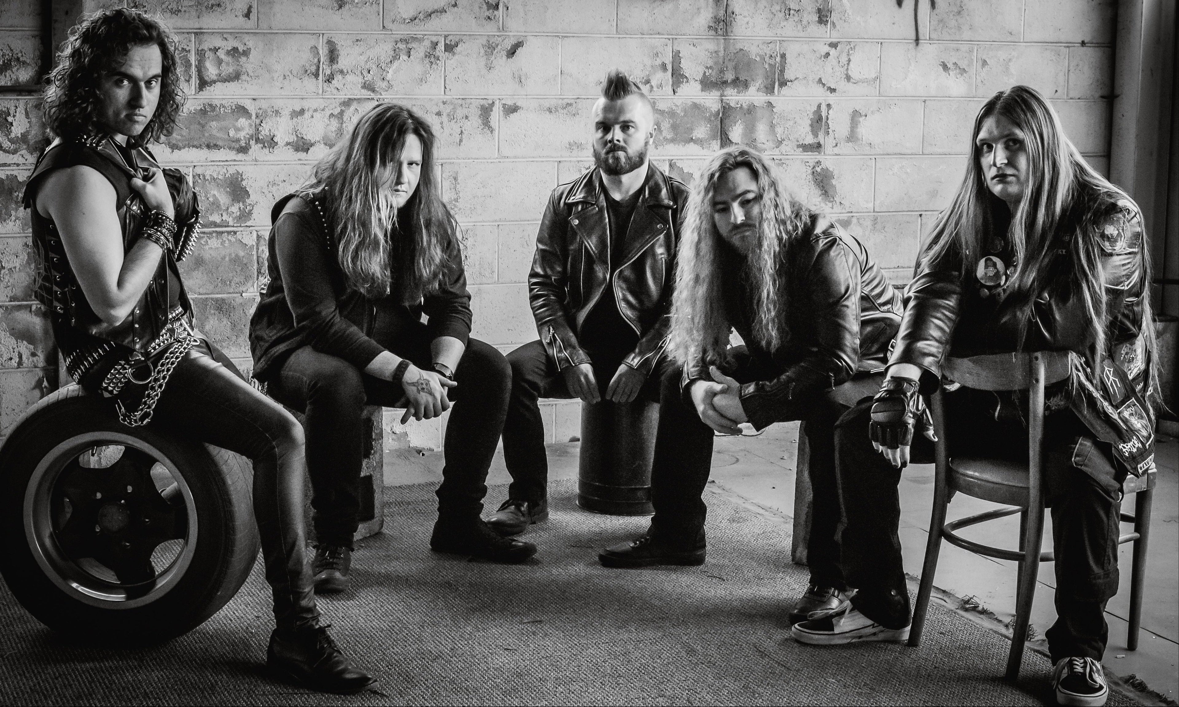 Black and white photo of five people sitting in a room with a rustic interior.