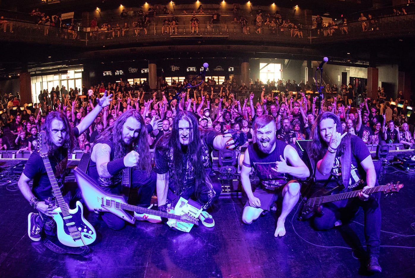 Music band posing on stage with a large audience in the background